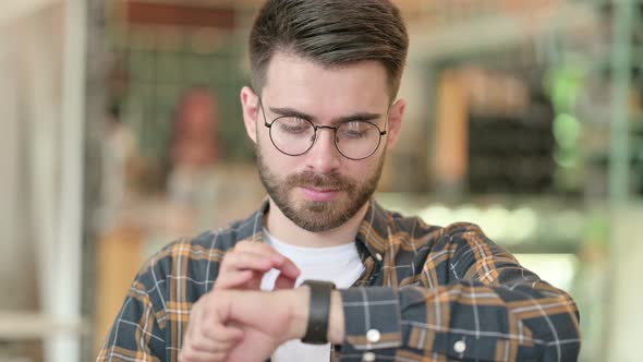 Portrait of Serious Young Man Using Smartwatch 