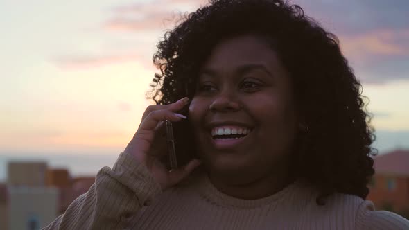 Young Afro Latin girl having call with mobile smartphone on house rooftop