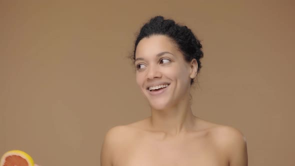 Beauty Portrait of Young African American Woman Having Fun with Half Grapefruit and Enjoying Its