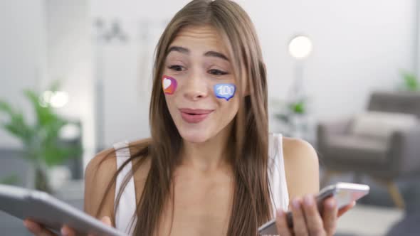 Portrait of Young Beautiful Woman with Painted Social Media Icons on Her Face Holding Phone