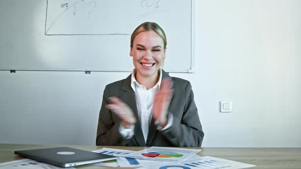 Young businesswoman in a suit clapping at the camera