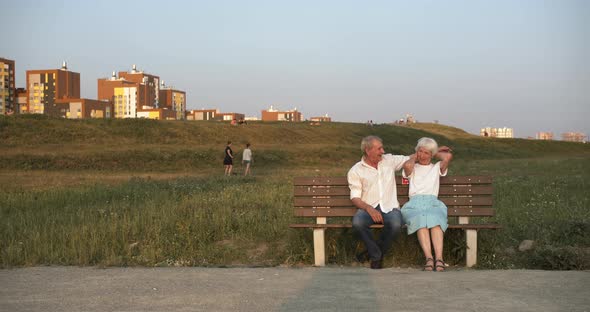 Gentle and Cheerful Hugs of an Elderly Couple on a Park Bench