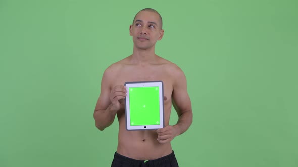 Happy Bald Multi Ethnic Shirtless Man Thinking While Showing Digital Tablet