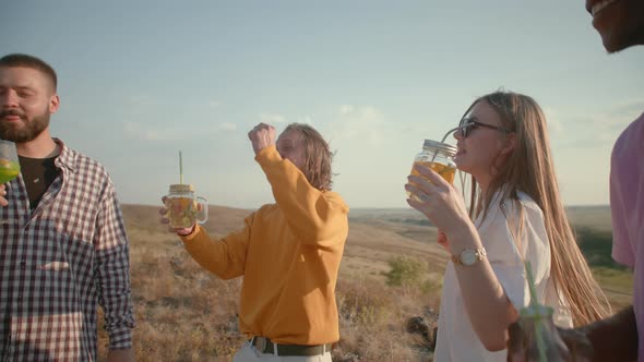 Emotional Team of Friends is Standing in Field Drinking Cocktails and Talking