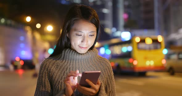 Young woman use of mobile phone in city at night