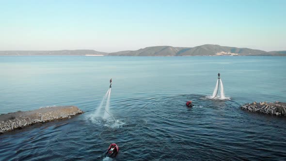 Aerial View of Training Flyboarding Team on Sea, Two Men Are Flying and Whirling in Air in Summer