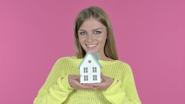 Beautiful Young Girl Holding Model House, Pink Background