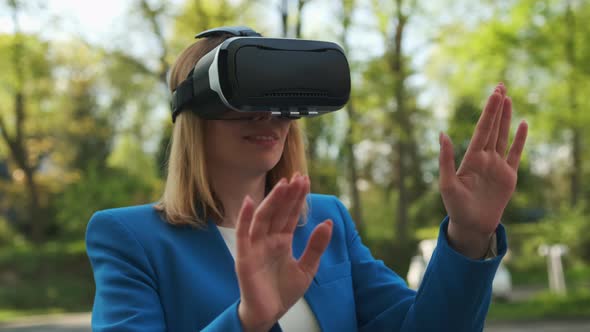 Business Woman Using VR Goggles Touching the Simulation Screen in the Park