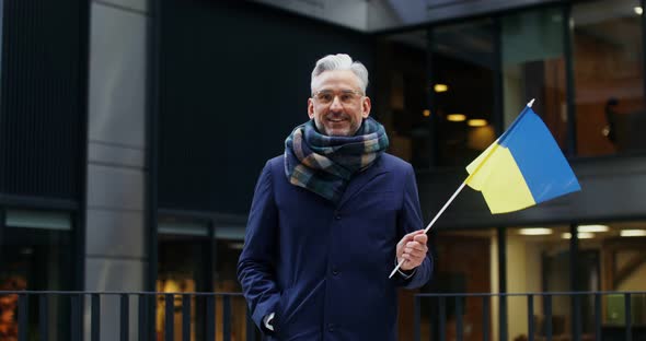 A Man Smiling Looking at the Camera Holding a Yellowblue Flag of Ukraine