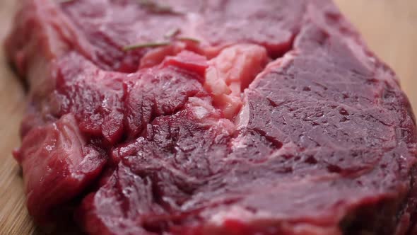 Dried rosemary Falling On Raw beef Steak On cutting Board