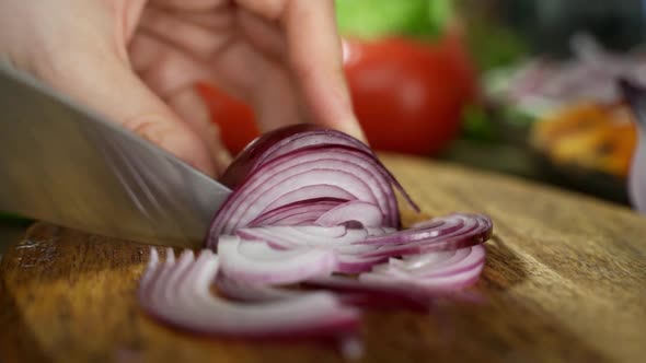 Chef Cuts Red Onions on a White Cutting Board with Big Knife on Small Pieces