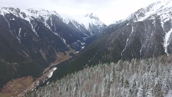 Fly Over a Large Snowy Forested Valley