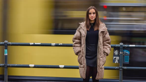 Time lapse of young woman standing in city street on autumn day looking at camera alone