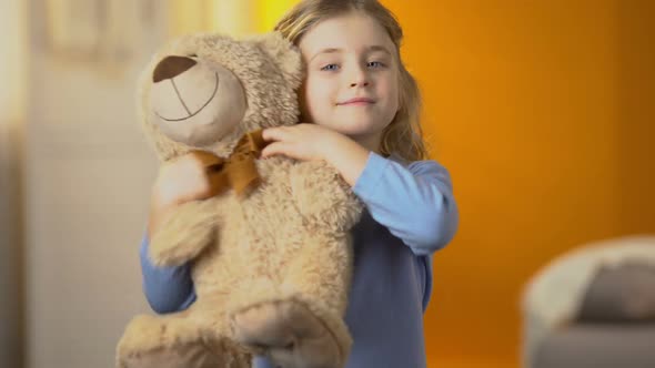 Curly-Haired Blond Girl Hugging Teddy Bear