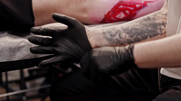 Tattoo Artist Putting on Black Gloves Before His Work