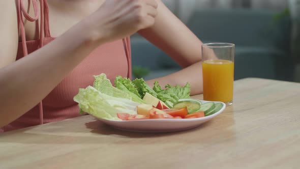 Woman With A Dish Of Healthy Food And A Glass Of Orange Juice Using A Fork Poking Cucumber