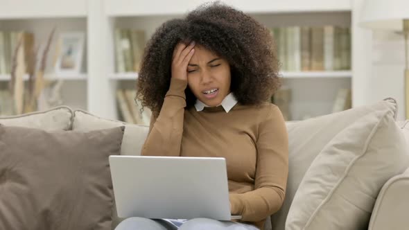 Young African Woman with Laptop Having Headache on Sofa