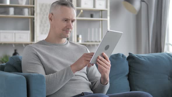 Gray Hair Man Browsing Internet on Tablet While Sitting on Couch