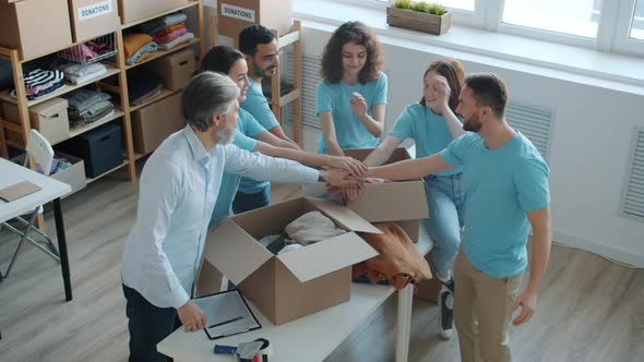 Group of Volunteers in Uniform Joining Hands Expressing Teamwork in Charity Fund Office