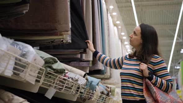 Young Female Choosing Curtains in Textile Shop