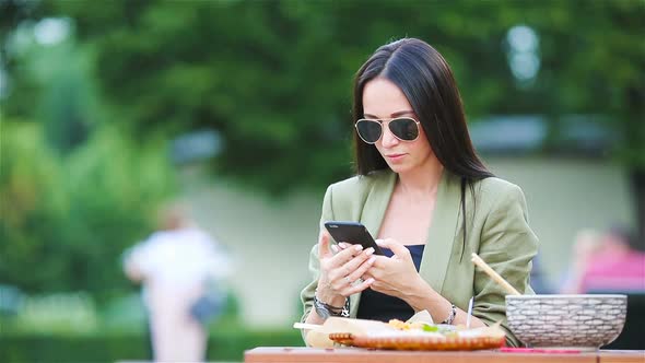 Young Woman Eating Take Away Noodles on the Street