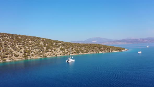 Catamaran and Sail Yachts Anchored at Bay on Deep Blue Sea Water on Sunrise