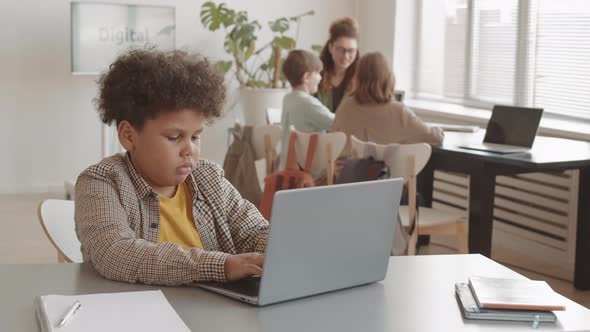 Mixed-Race Boy Using Laptop in Classroom