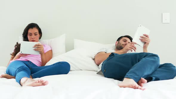 Couple using digital tablet on bed in the bedroom