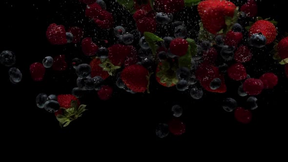 Slow Motion Strawberry Raspberries and Blueberry Falling Into Transparent Water