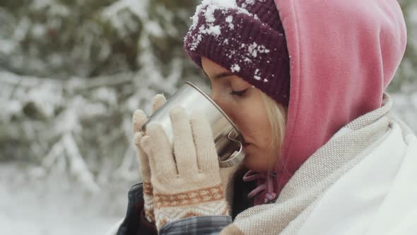 Young Woman Drinking Hot Tea Outdoors on Winter Day