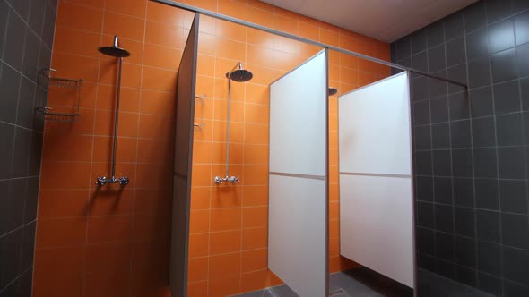 Empty Shower Cabins with New Equipment and Orange Tiled Wall