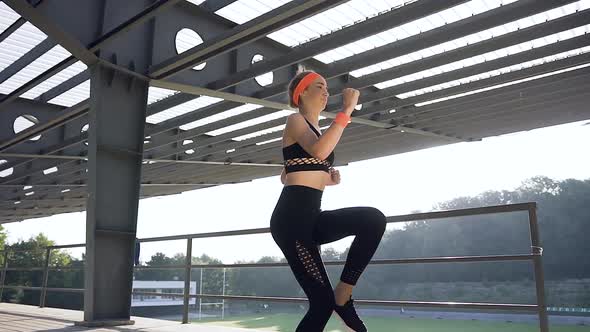 Athletic Young Girl in Fitness Clothes Running on the Spot During Her Training Outdoors