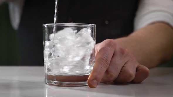 The Bartender Cools the Glass. A Man Interferes with Ice Cubes in a Cocktail Glass.