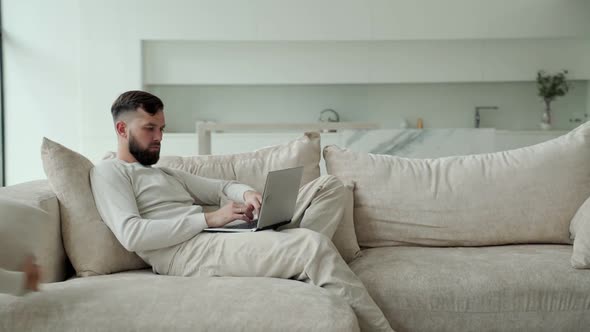 Young Father Works Remotely at Home at His Laptop Due to the Coronavirus Pandemic