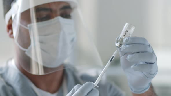 Doctor in Protective Uniform Drawing Vaccine out with Syringe