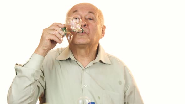 Senior Cheerful Man Blowing Bubbles Isolated on White
