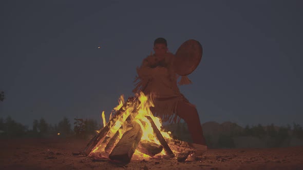 A Shaman with a Drum Jumps in Around the Fire in Clothes for the Ceremony