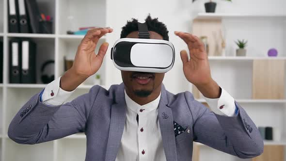 African American Putting on Virtual Reality Headset and Working on imaginary screen