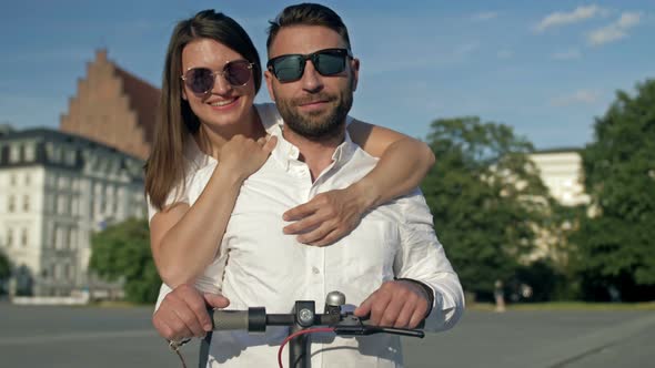 Summer Portrait of a Couple in Love on an Electric Scooter