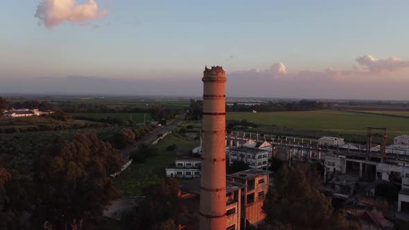 Aerial drone orbiting a tower in a huge abandoned factory at sunset, Seville, Spain.