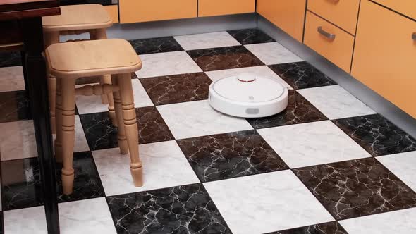 Robot Vacuum Cleaner Cleans in the Modern House on the Floor at Kitchen