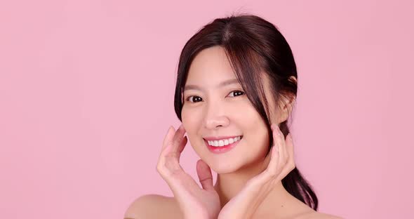 Close up Slow motion Beauty shot of Beautiful Asian girl looking at camera on pink background