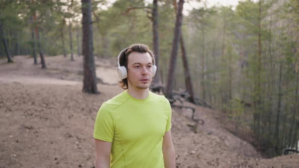 Runner in Headphones Watches Landscape During Training Break