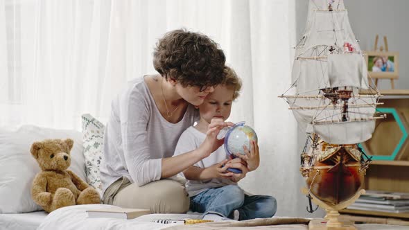 Mother Showing Desk Globe to Son alt