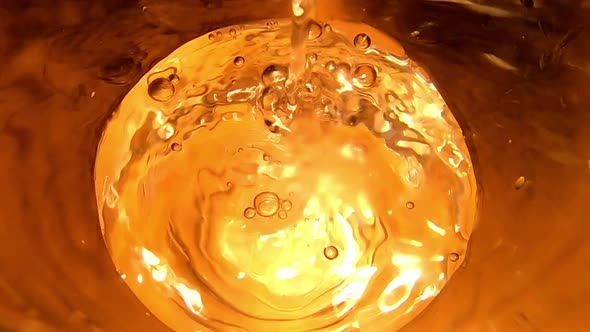 Slomo shot of water being poured into glass. Top view, close up