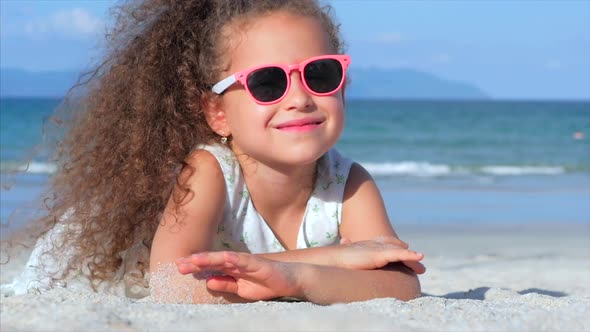 Portrait of a Beautiful Little Girl in Pink Glasses, Cute Smiling Looking at the Camera