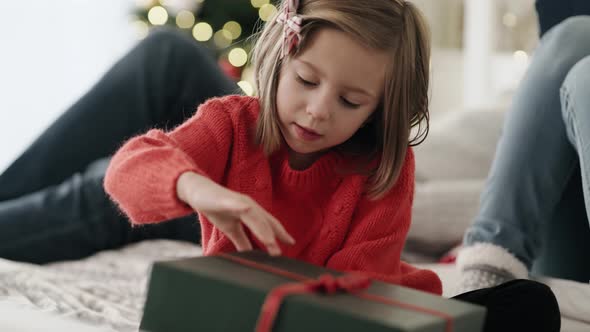 Video of child opening  gift and parents in the background. Shot with RED helium camera in 8K. 