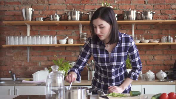 Woman Housewife in the Kitchen Trying Spoiled the Dish with a Spoon Out of the Pan