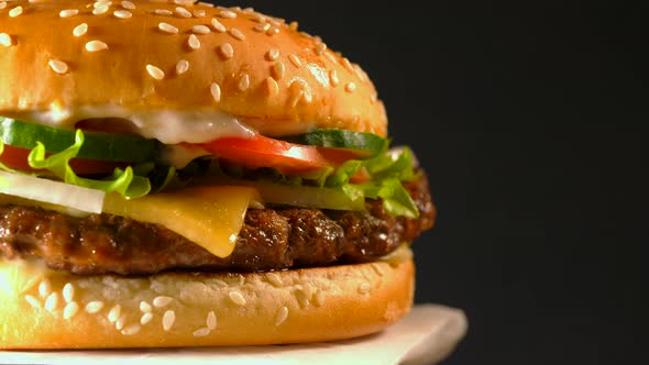 Big appetizing burger with meat cutlet. Isolated hamburger on dark smoke background, close-up view