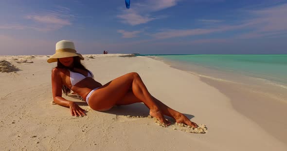 Young smiling lady on holiday by the sea on the beach on summer white sand and blue 4K background